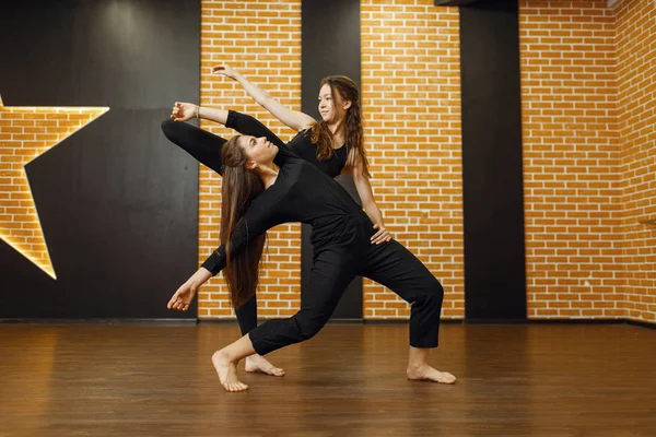 Two female contemporary dance performers in studio. Dancers training in class, modern elegance dancing, stretching exercise
