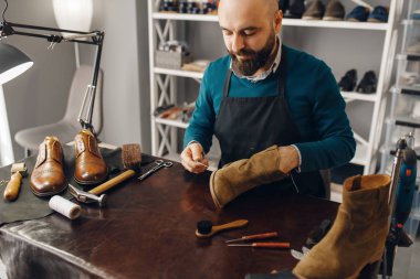 Ayakkabı tamircisi ayakkabıyı diker, ayakkabı tamir hizmeti verir. Zanaatkarlık yeteneği, ayakkabı yapma atölyesi, usta çizmelerle çalışır.