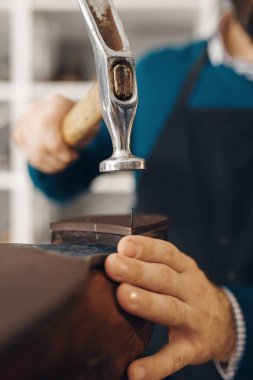Ayakkabıcı ayakkabının topuğunu vuruyor, ayakkabı tamir servisi. Zanaatkarlık yeteneği, ayakkabı yapma atölyesi, usta çizmelerle çalışır, ayakkabı tamirciliği.