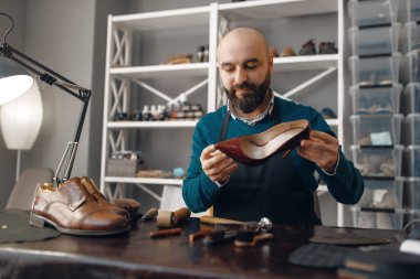 Ayakkabı tamircisi, ayakkabı tamiri servisi. Zanaatkarlık yeteneği, ayakkabı yapma atölyesi, usta çizmelerle çalışır, ayakkabı tamirciliği.