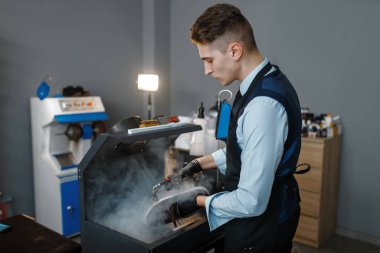 Ayakkabı üreticisi ayakkabıları özel bir makineye yerleştirir, ayakkabı tamir hizmeti verir. Zanaatkarlık yeteneği, ayakkabı yapma atölyesi, usta çizmelerle çalışır, ayakkabı tamircisi.