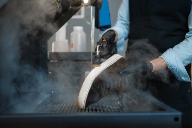 Ayakkabı tamircisi ayakkabıları özel makinede, ayakkabı tamir servisinde inceler. Zanaatkarlık yeteneği, ayakkabı yapma atölyesi, usta çizmelerle çalışır.