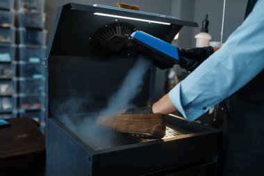 Ayakkabı tamircisi ayakkabıları özel makinede, ayakkabı tamir servisinde inceler. Zanaatkarlık yeteneği, ayakkabı yapma atölyesi, usta çizmelerle çalışır, ayakkabı tamircisi.