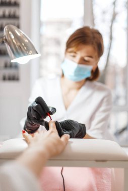 Kozmetoloji salonu, manikür, vernik uygulama prosedürü. Güzellik mağazasında kadın müşteri için el bakımı tedavisi, kozmetolojist kadın, tırnakile usta çalışır