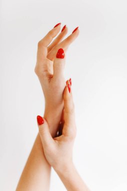 Beyaz arka planda kırmızı manikürlü güzel kadın elleri var. Güzellik salonu, profesyonel hizmet. Spa stüdyosunda tırnak bakımı sonrası kadın müşteri elleri