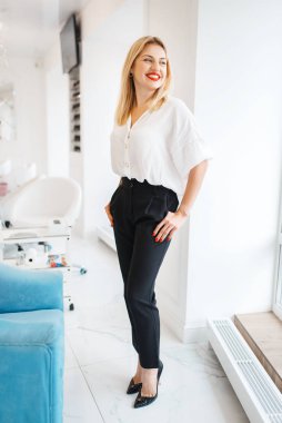 Attractive woman poses in beauty salon. Professional beautician service, happy female customer after makeup, manicure and pedicure procedure in spa studio