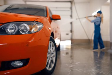 Üniformalı kadın yıkama, yüksek basınçlı tabancayla tekerlekleri temizler, araba yıkama, araba yıkama, araba yıkama, araba yıkama.