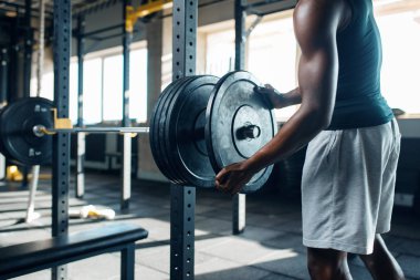 Spor giyimli kaslı adam halteri spor salonunda eğitime hazırlıyor. Spor kulübünde egzersiz, sağlıklı bir yaşam tarzı.