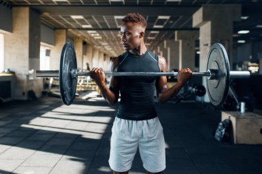 Spor giyimli kaslı bir sporcu spor salonunda halterle egzersiz yapıyor. Spor kulübünde egzersiz, sağlıklı bir yaşam tarzı.