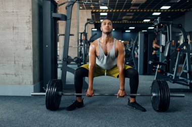 Spor giyimli bir sporcu spor salonunda halterle egzersiz yapıyor. Spor kulübünde egzersiz, sağlıklı bir yaşam tarzı.