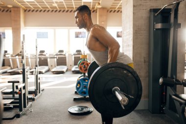 Spor giyimli bir sporcu spor salonunda halterle egzersiz yapıyor. Spor kulübünde egzersiz, sağlıklı bir yaşam tarzı.