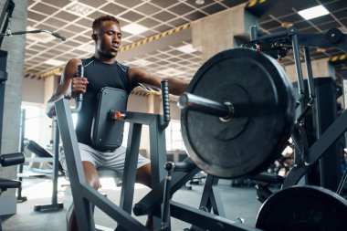 Spor giyimli kaslı sporcu spor salonunda egzersiz makinesinde. Spor kulübünde egzersiz, sağlıklı bir yaşam tarzı.