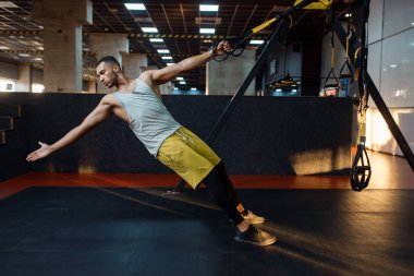 Spor giyim bölümünde spor salonunda kaslı bir sporcu spor salonunda egzersiz makinesini esnetiyor. Spor kulübünde egzersiz, sağlıklı bir yaşam tarzı.