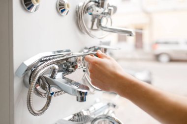 Tesisatçı dükkanındaki vitrinde üniformalı bir tesisatçı. Defterli bir adam dükkandan hijyen mühendisliği satın alıyor, musluklar ve musluklar tercih ediliyor.