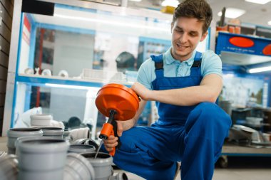 Tesisatçı dükkanındaki vitrindeki üniformalı hijyenik teknisyen. Tesisatçı dükkanda, kanalizasyon borularında tesisat satın alıyor ve adaptör seçimi yapıyor.