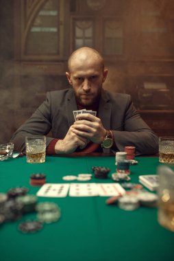 Takım elbiseli poker oyuncusu kumarhanede oynuyor, risk bağımlısı. Şans oyunları işte. Kumarhanede boş vakitler, yeşil kumaşlı kumar masası.