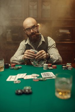 Sakallı poker oyuncusu, puro ve kumarhane. Şans oyunları bağımlılığı. Kumarhanede adam boş vakit geçirir. Kumar masasında kağıt, cips ve viski.