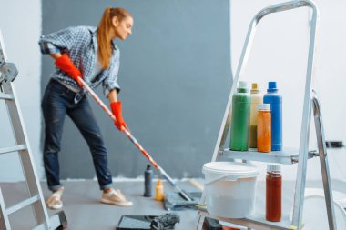 Female house painter paints walls indoor. Home repair, laughing woman doing appartment renovation, room decoration renovating