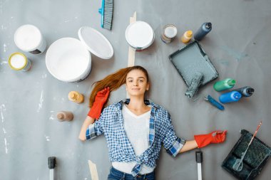 Neşeli kadın boyacı yerde yatıyor, manzarası çok güzel. Ev onarımı, mutlu bir kadın apartman onarımı, oda dekorasyonu.
