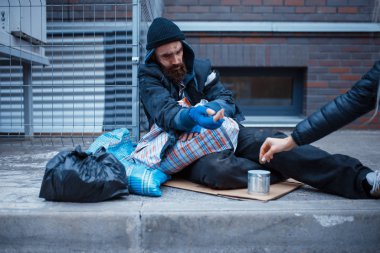 Male bearded beggar begging on city street. Poverty is a social problem, homelessness and loneliness, alcoholism and  drunk addiction, urban lonely