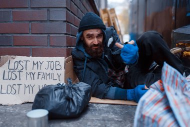 Bearded beggar sleeping on city street. Poverty is a social problem, homelessness and loneliness, alcoholism and drunk addiction