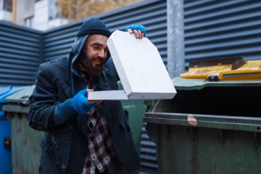 Sakallı pis dilenci, şehirdeki çöp tenekesinde pizza bulmuş. Yoksulluk sosyal bir sorundur, evsizlik ve yalnızlık, alkolizm ve sarhoş bağımlılığı, şehir yalnızlığı.