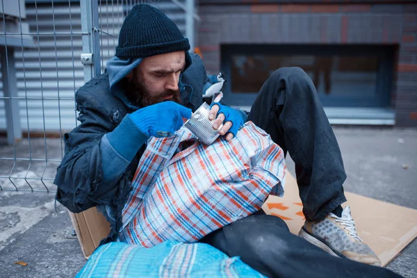 髭を生やした男が街の通りで食べる 貧困は社会問題 ホームレスや孤独 アルコール依存症や飲酒依存症 都市部の孤独 — ストック写真