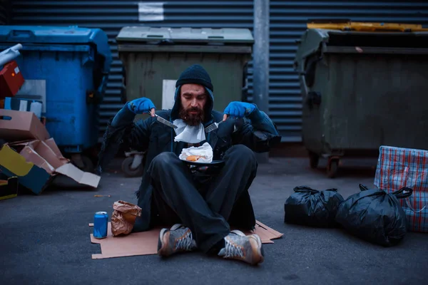 ナイフで汚れた乞食ひげとフォークは街の通りのゴミ箱で食べます 貧困は社会問題 ホームレスや孤独 アルコール依存症や飲酒依存症 都市部の孤独 — ストック写真