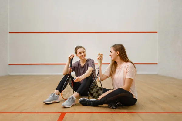 Duas Jogadoras Com Raquetes Squash Sentam Chão Quadra Meninas Treinamento — Fotografia de Stock