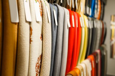 Vitrindeki renkli kumaş tekstili. Yakın çekim, kimse yok. Dikiş dikmek için kumaş rafı, mağazada kıyafet seçimi.