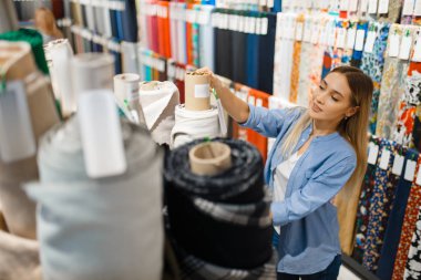 Terzi kadın tekstil atölyesinde kumaş sarma dersi alıyor. Kadın dikiş dikmek için kumaşla çalışıyor, kadın terzi, terzi.