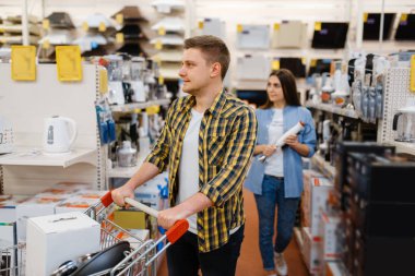 Genç çiftin elektronik mağazasında elektrikli blenderi var. Erkek ve kadın marketten ev aletleri satın alıyorlar.