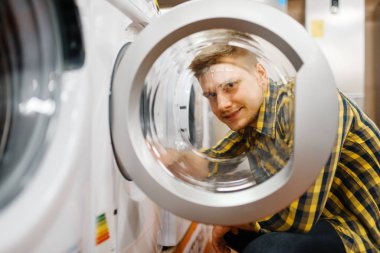 Elektronik mağazasından çamaşır makinesini seçen adam. Erkek kişi marketten ev aletleri satın alıyor
