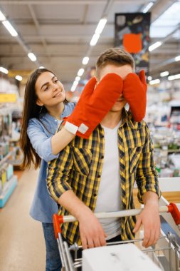 Genç, oyuncu bir çift, mağazadan alışveriş yapıyorlar. Erkek ve kadın marketten ev eşyaları alıyor, aile mutfak gereçleri dükkanında.