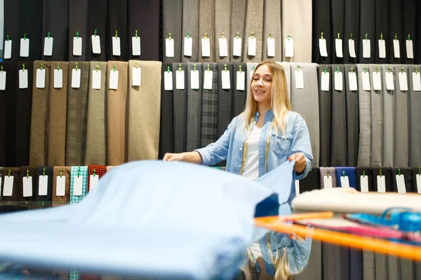 Smiling Seamstress Holds Fabric Textile Store Shelf Cloth Sewing Background — 스톡 사진