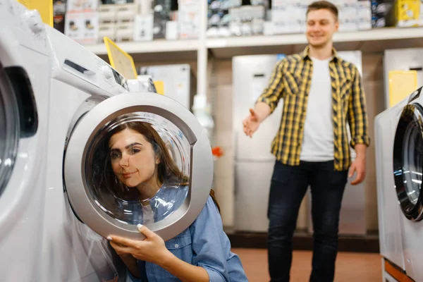 Woman choosing washing machine in electronics store. Female person buying home electrical appliances in market