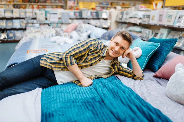 年轻人躺在床上用品商店的床上 男人在市场上买家居用品 男人在商店里睡觉 — 图库照片