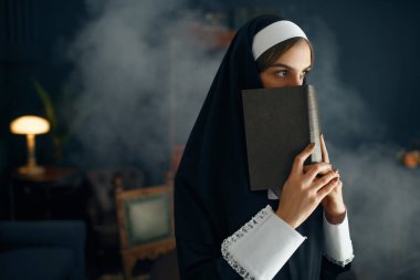 Cüppeli genç rahibe bir kitap tutuyor. Rahibe manastırda ibadet için hazırlanıyor, din ve inanç, dindar insanlar.