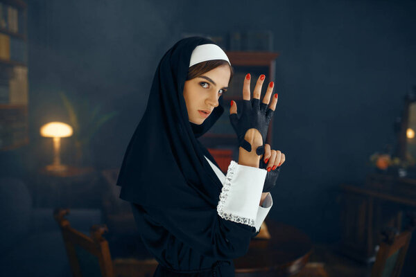 Young sexy nun in a cassock puts on a glove, vicious desires. Corrupt sister in the monastery, religion and faith, sinful religious people, attractive sinner