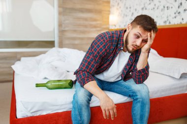 Sarhoş adam yatakta bir şişe şarapla uyandı. İçki sersemliği, baş ağrısı ve depresyon geçiren erkek, kötü bir sabah.