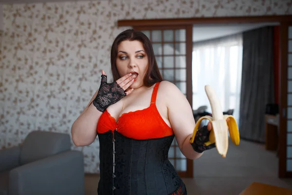 穿着情色内衣的肥胖变态女人惊讶地看着香蕉 性感的超重女孩 丰满的乳房 腐败的大块头女士 — 图库照片