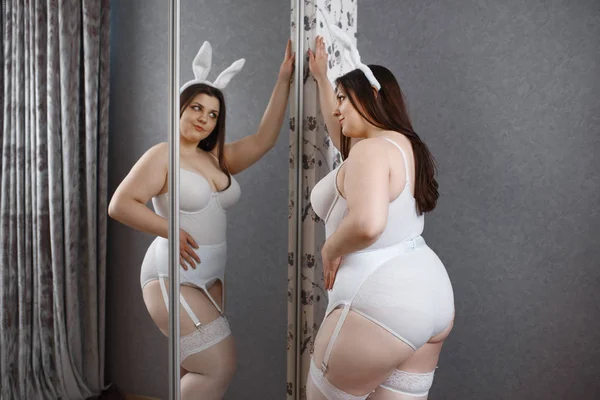 オーバーウェイトの堕落した女がエロいウサギの衣装で鏡にポーズ セクシーな太りすぎの女の子とともに大きな胸 逆に大きなサイズ女性 — ストック写真