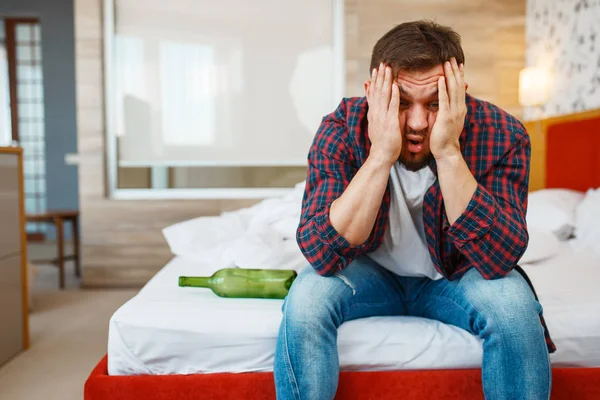 Sarhoş adam yatakta bir şişe şarapla uyandı. İçki sersemliği, baş ağrısı ve depresyon geçiren erkek, kötü bir sabah.