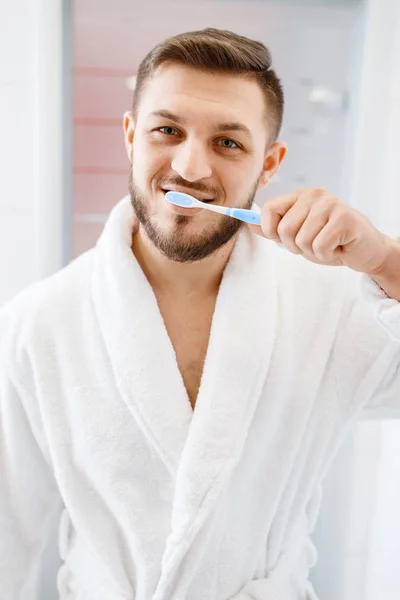 穿着浴衣的男人在浴室里刷牙 这是每天早上的卫生习惯 水槽处的男性进行皮肤和身体治疗 — 图库照片