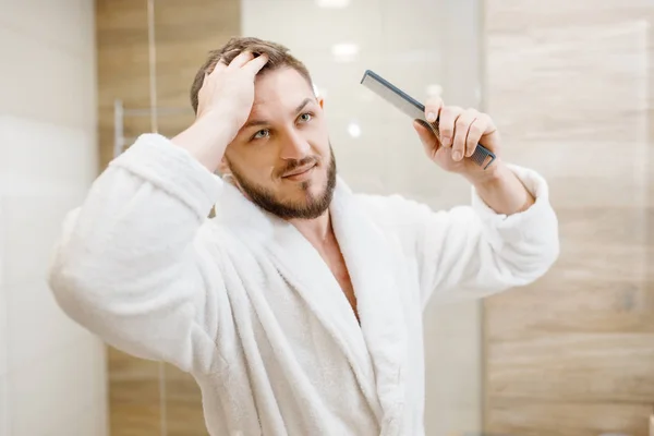 穿着浴衣的男人在浴室里梳头 每天早上都很卫生 水槽处的男性进行皮肤和身体治疗 — 图库照片