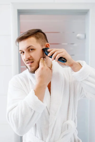 Hombre Albornoz Afeita Barba Con Una Afeitadora Eléctrica Baño Higiene — Foto de Stock