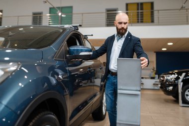 Adam araba galerisindeki taşımacılık konfigürasyonunu inceliyor. Yeni araç galerisindeki müşteri, otomobil alan erkek, otomobil satıcısı.