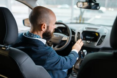 Adam araba galerisindeki yeni otomobilin içini inceliyor. Araç galerisinde müşteri, ulaşım satın alan erkek, otomobil satıcısı.