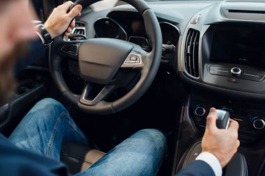 Araba galerisindeki yeni otomobil direksiyonundaki adam. Araç galerisinde müşteri, ulaşım satın alan erkek, otomobil satıcısı.