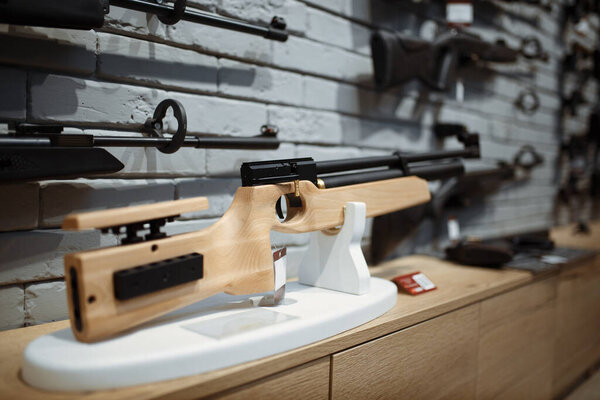Pneumatic rifles on showcase in gun shop closeup, nobody. Euqipment for hunters on stand in weapon store, hunting and sport shooting hobby 